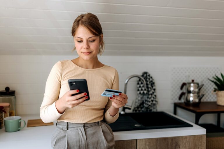 Young-woman-on-her-smart-phone-at-home-while-holding-credit-card_-Pekic.jpg